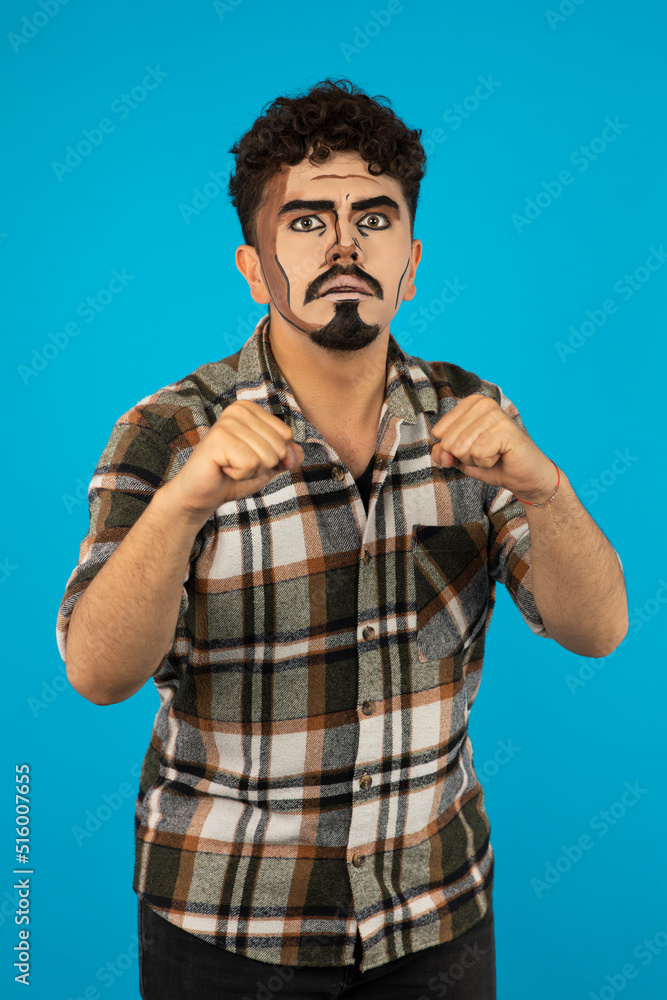 Naklejka premium Young man with pop-art makeup squeezed his fists and looking at cmaera