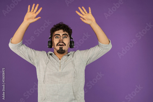 Young creative guy holding his hands up and listening music