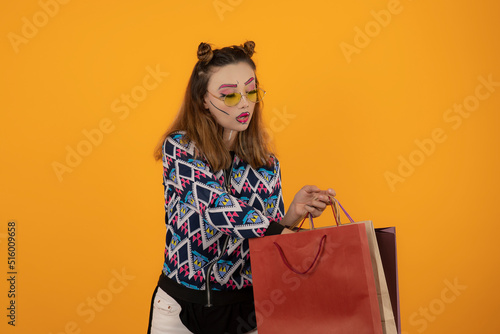 Creative beautiful girl holding shopping bags and ] looking inside of bag