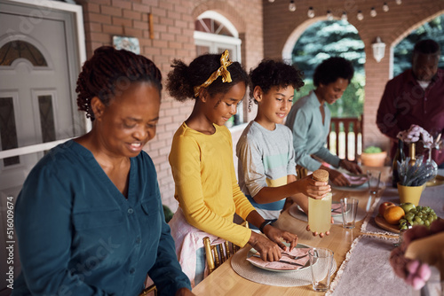African American multi-generation family setting dining table on patio.