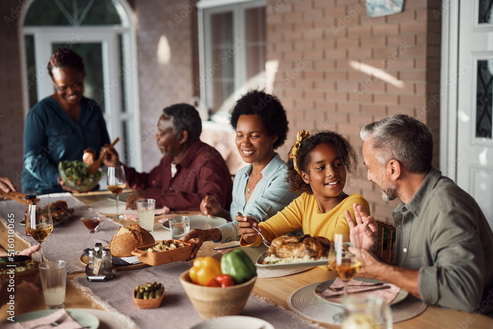 Happy multiethnic family enjoys while having meal at dining table on patio. Happy multiethnic family enjoys while having meal at dining table on patio.