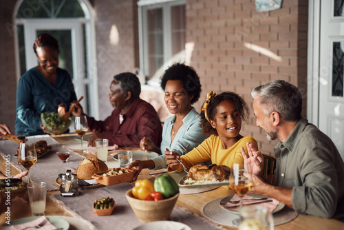 Happy multiethnic family enjoys while having meal at dining table on patio.