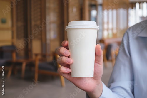 Man hand holding paper cup of hot coffee in coffee cafe. take away hot drink.