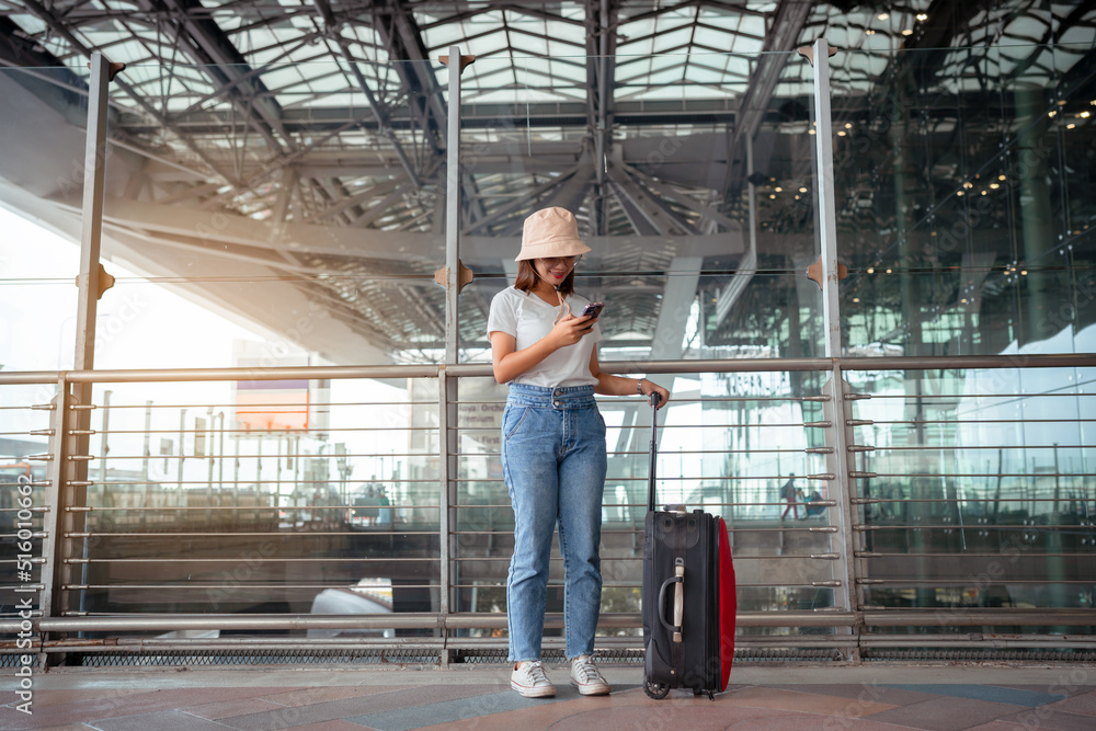 Traveler with suitcase in airport concept.Young girl using smartphone with carrying luggage and passenger for tour travel booking ticket flight at international vacation, rest and relaxation.