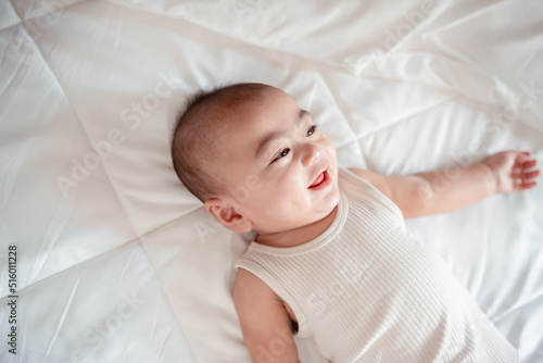 Smiling of newborn baby or cute little lying on a white bed at home. Infant child portrait happy concept, Healthy childcare in the morning.