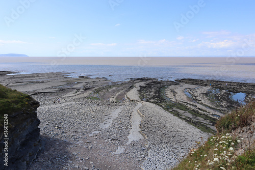 A few people wander around Kilve beach near East Quantoxhead in Somerset, England looking for fossils. Strata of rock dating back to the Jurassic era form cracked pavements along the beach. photo