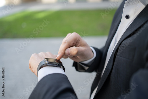 Uses a smart watch a male manager working from the office in a suit