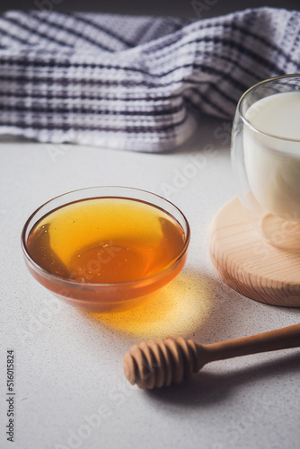 Milk and honey. Glass cup with milk and bowl with honey on the table. Spoon for honey. Breakfast, snack. Calming and healthy drink.
