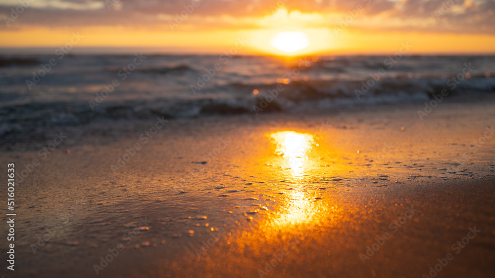 Sonnenuntergang am Strand mit Lichtreflexion im Sand