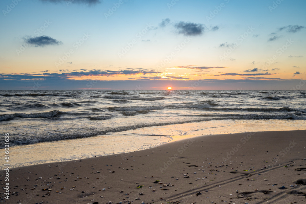 Wunderschöner Sonnenuntergang am Strand mit Blick auf die Wellen im Meer