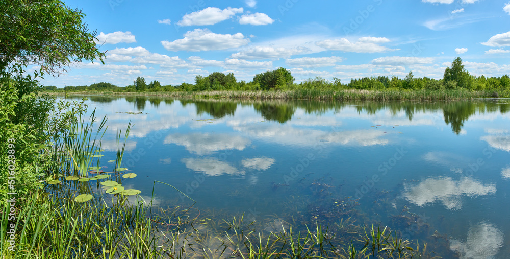 Peaceful summer panorama landscape with clouds on the blue sky and reflection in the river near Kyiv city in Ukraine.