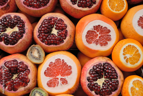 Close view of cutted garnet end orange fruites on market.