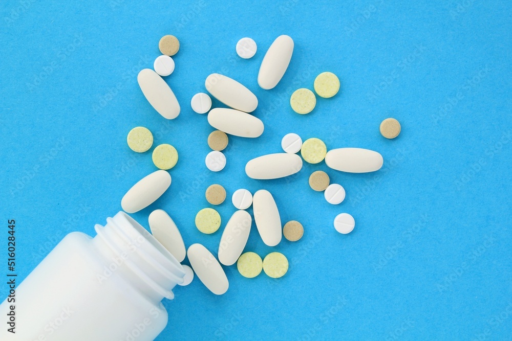 Tablets, capsule, pills and white plastic pack on blue background. Vitamin prescription supplement, drugs, Pharmaceutical medicine health therapy idea. Suicide abuse overdose concept. Doping steroid Tablets, capsule, pills and white plastic pack on blue background. Vitamin prescription supplement, drugs, Pharmaceutical medicine health therapy idea. Suicide abuse overdose concept. Doping steroid