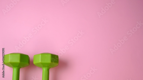 Two dumbbells for home workout on light pink background. Exercise fitness concept. Space for text.