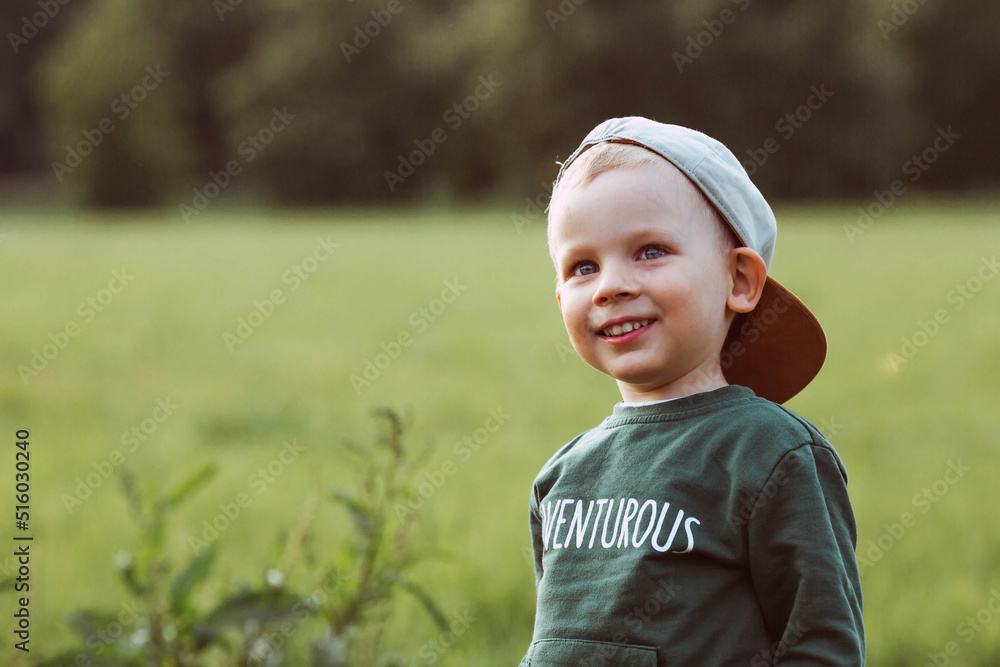 Portrait of a cute boy sitting on a green grass field. Baby's emotions, happiness, funny emotions on his face. The concept of childhood. sunny spring summer day. Portrait of a cute boy sitting on a green grass field. Baby's emotions, happiness, funny emotions on his face. The concept of childhood. sunny spring summer day.