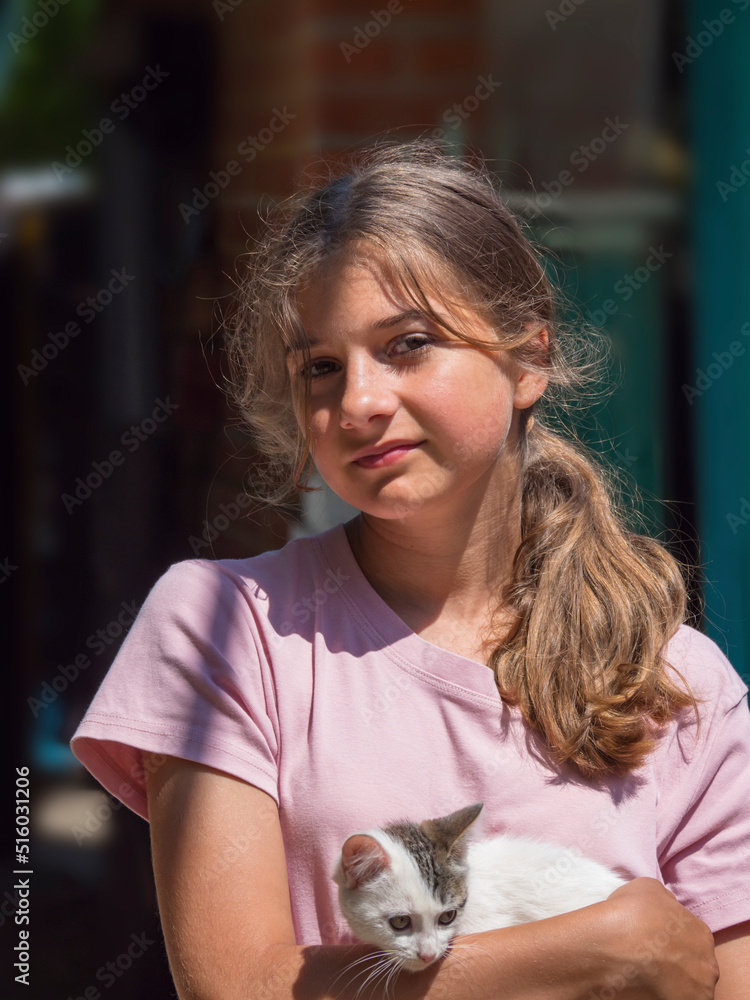 Portrait of a beautiful girl with a kitten in her arms. A cute teenage girl looks into the camera and hugs a cute little kitten. Young smiling Caucasian girl outdoors hugs a cute cat Portrait of a beautiful girl with a kitten in her arms. A cute teenage girl looks into the camera and hugs a cute little kitten. Young smiling Caucasian girl outdoors hugs a cute cat
