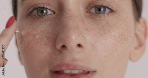Beautiful young woman applying rejuvenating serum at her face