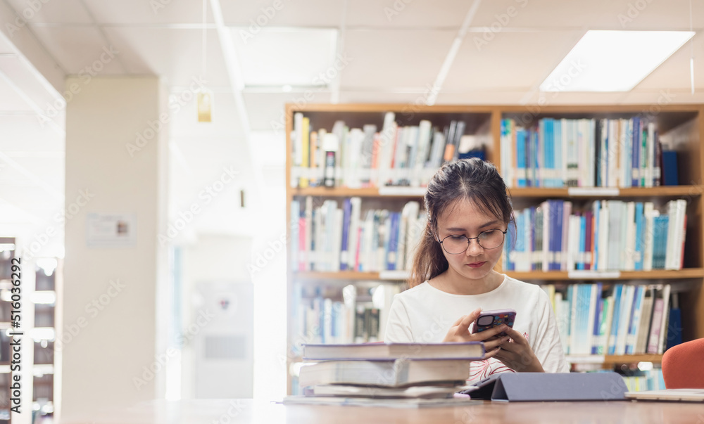 Asian woman Searching the Internet using a smartphone in the library. Asian woman Searching the Internet using a smartphone in the library.