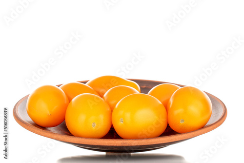 Several ripe yellow tomatoes on a ceramic plate, close-up, isolated on a white background.