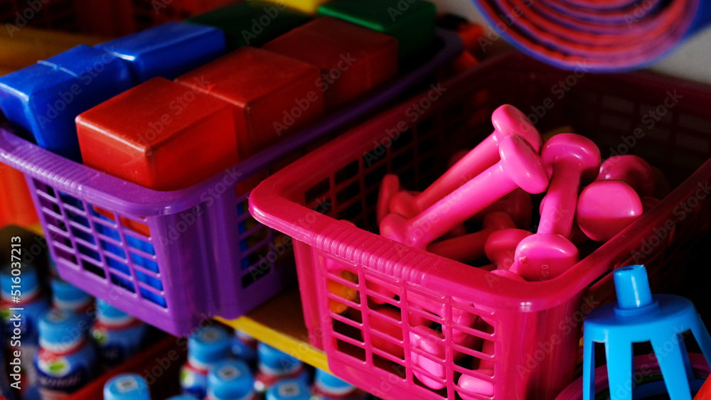 Children's dumbbells lie in a basket in the gym of the kindergarten