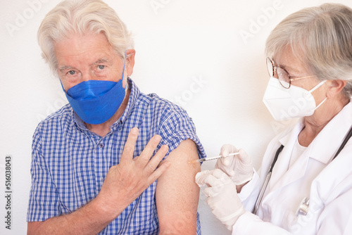 Doctor giving injection to senior caucasian man, old retired receiving fourth booster of covid 19 vaccine, people wearing mask