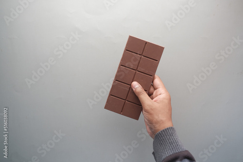 top view of men golding a dark chocolate on gray background 