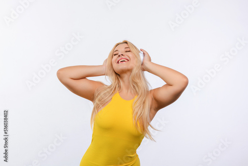 young beautiful girl with white hair in a yellow dress listens to music on a white background