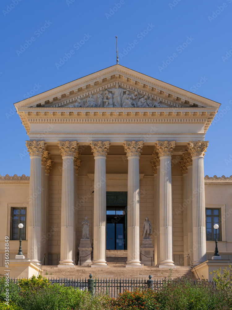 Vertical view of the neoclassical stone facade with columns and pediment representing Justice of the historic courthouse, a landmark of Montpellier, France