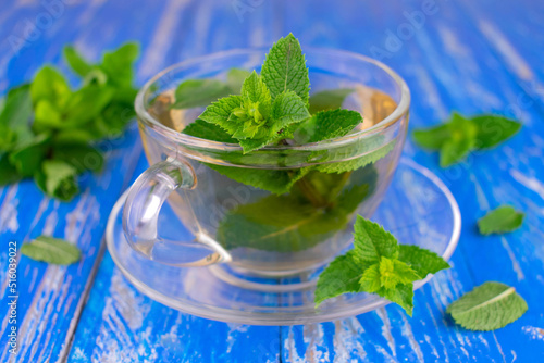 A cup of soothing mint tea on a wooden blue background.