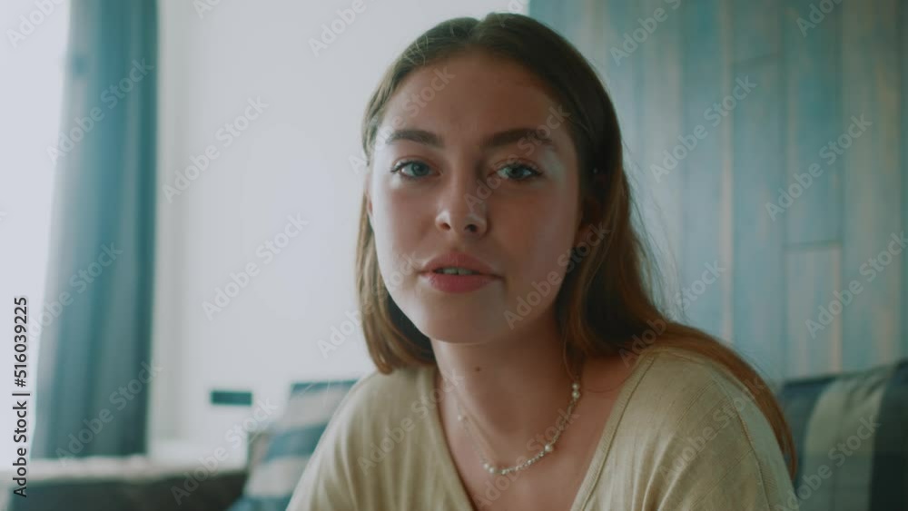 Close up young woman looking at camera talking having online video chat conference. Webcam view. Sitting on sofa blogging. Slow motion Close up young woman looking at camera talking having online video chat conference. Webcam view. Sitting on sofa blogging. Slow motion