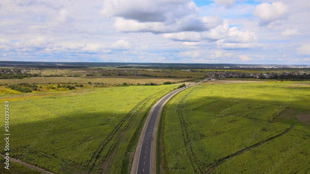 Aerial view of intercity road between green agricultural fields with fast driving cars. Top view from drone of highway traffic Aerial view of intercity road between green agricultural fields with fast driving cars. Top view from drone of highway traffic