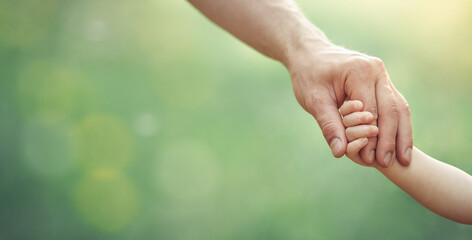 Fathers hand holding his little child in sunny day outdoor, united family and happy childhood concept, banner format