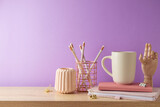 Stylish feminine table with coffee cup, notebook and pencils over purple background. Back to school concept