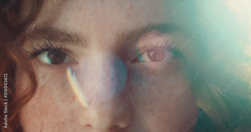Close up eyes sunshine young smiling woman with red curly hair look at camera. Feel happy. Summer. Outdoors at sunlight. Slow motion