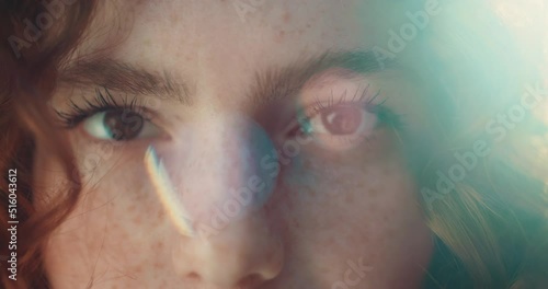 Close up eyes sunshine young smiling woman with red curly hair look at camera. Feel happy. Summer. Outdoors at sunlight. Slow motion