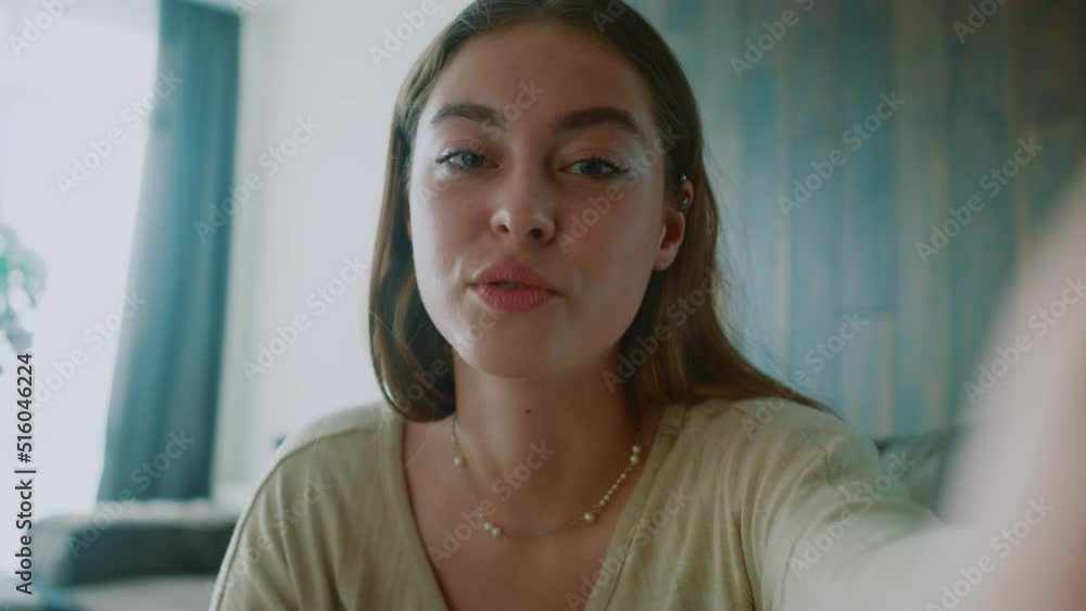 Portrait face young woman looking at camera talking having online video chat conference. Webcam view. Sitting on sofa blogging. Slow motion Portrait face young woman looking at camera talking having online video chat conference. Webcam view. Sitting on sofa blogging. Slow motion