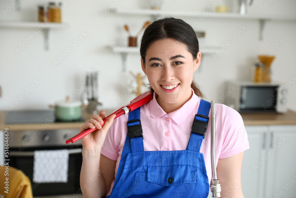 Asian female plumber with pipe wrench in kitchen Asian female plumber with pipe wrench in kitchen