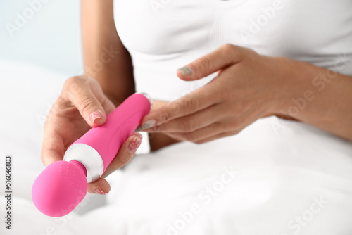 Young woman with vibrator sitting in bed, closeup photo