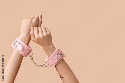 Female hands with handcuffs from sex shop on color background © Pixel-Shot