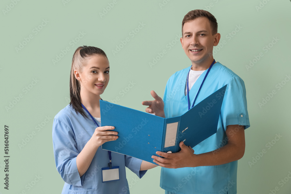 Medical assistants with folder on green background Medical assistants with folder on green background