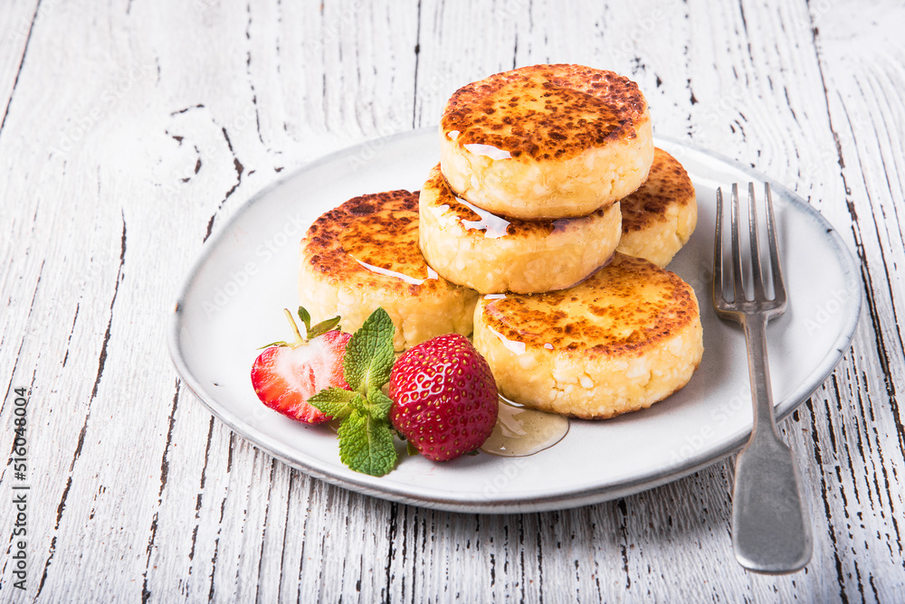 Cheesecakes with strawberries and honey on a white table. Cheesecakes with strawberries and honey on a white table.