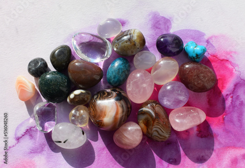 Gemstones of various colors. Amethyst, rose quartz, agate and rock crystal on a pink watercolor background