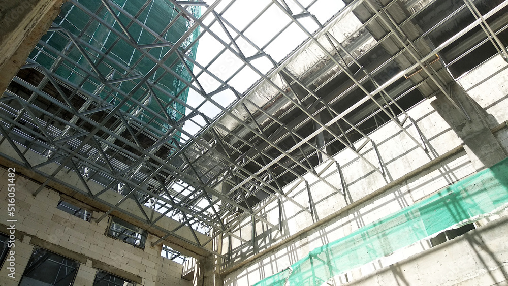 SELANGOR, MALAYSIA -JUNE 16, 2021: Construction workers install trusses and roofing sheets at construction sites. Lightweight roof trusses used are more economical, sturdy and fast.