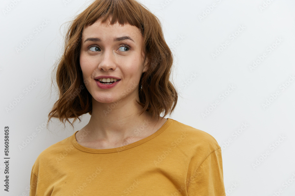 a beautiful, sweet, relaxed woman stands on a light background in a yellow T-shirt and looks away with a pleasant smile. Horizontal photo with an empty space for inserting an advertising layout a beautiful, sweet, relaxed woman stands on a light background in a yellow T-shirt and looks away with a pleasant smile. Horizontal photo with an empty space for inserting an advertising layout