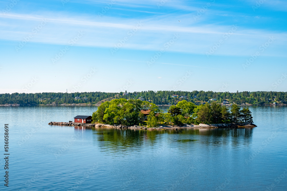 Idyllic scenery of houses on island against blue sky. Picturesque scenery of Archipelago in Baltic Sea. View of Swedish lifestyle with beautiful natural landscape.