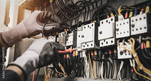 Tela Electricity and electrical maintenance service, Engineer hand holding AC multimeter checking electric current voltage at circuit breaker terminal and cable wiring main power distribution board