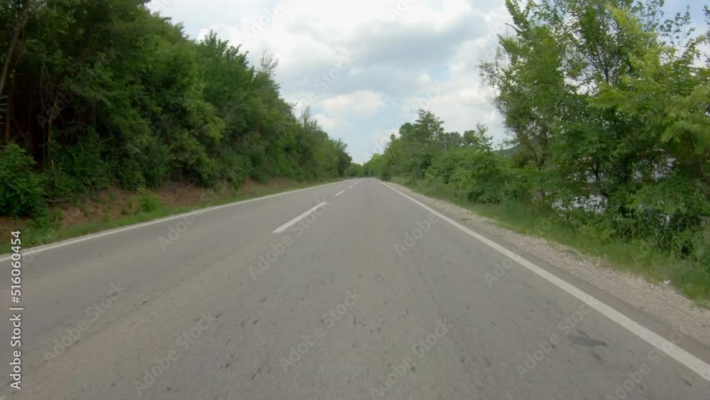Driving a car or motorcycle on a country road uphill surrounded by trees. Point of view shot Driving a car or motorcycle on a country road uphill surrounded by trees. Point of view shot
