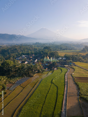 Aerial photo of Mosque with golden dome in the middle of rice field and mountain on the background. Kajoran rice field, Central Java, Indonesia
