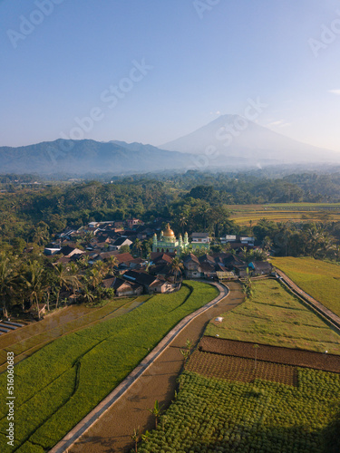 Aerial photo of Mosque with golden dome in the middle of rice field and mountain on the background. Kajoran rice field, Central Java, Indonesia