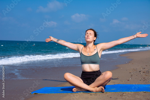 A beautiful girl is doing yoga on the beach near the sea